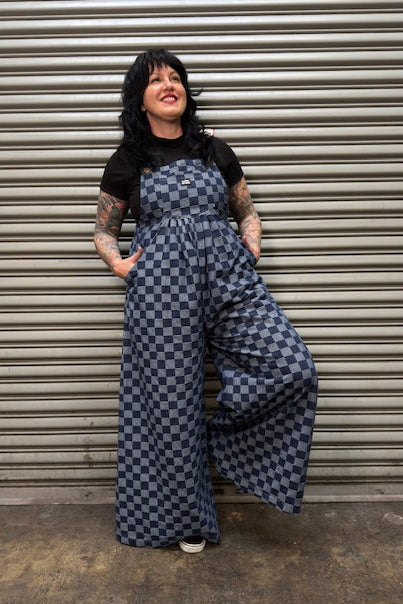 Person wearing a checkered jumpsuit standing in front of a metal shutter.