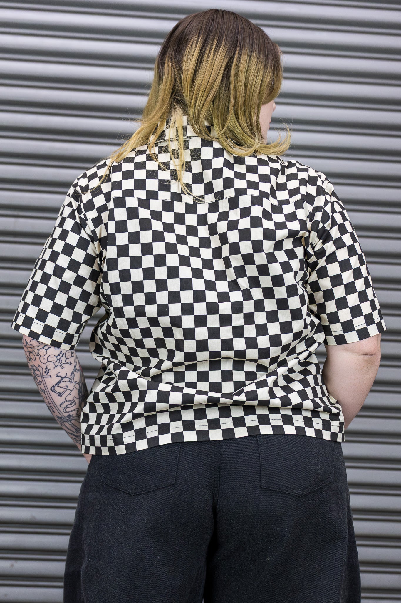 Person wearing a black and white checkered shirt against a metallic background