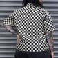 Person wearing a black and white checkered shirt in front of a metallic shutter.