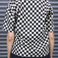 Person wearing a black and white checkered shirt against a metallic shutter background