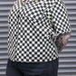 Person wearing a black and white checkered shirt with a blurred background