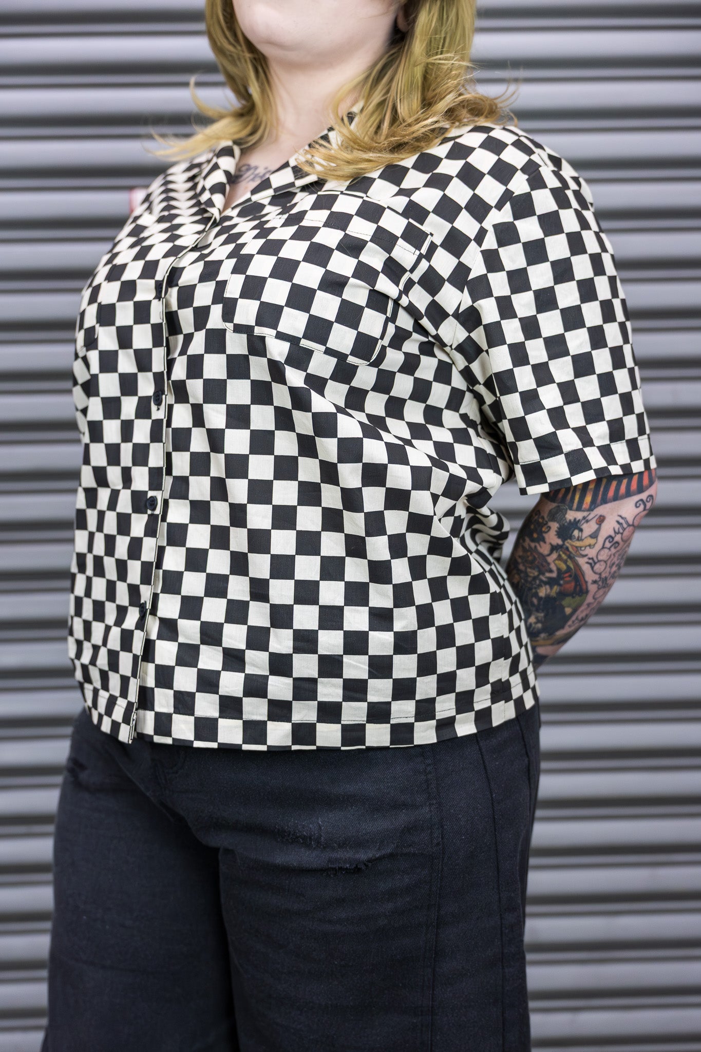 Person wearing a black and white checkered shirt with a blurred background