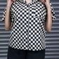 Person wearing a black and white checkered shirt against a metallic shutter background
