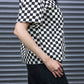 Person wearing a black and white checkered shirt against a metallic shutter background