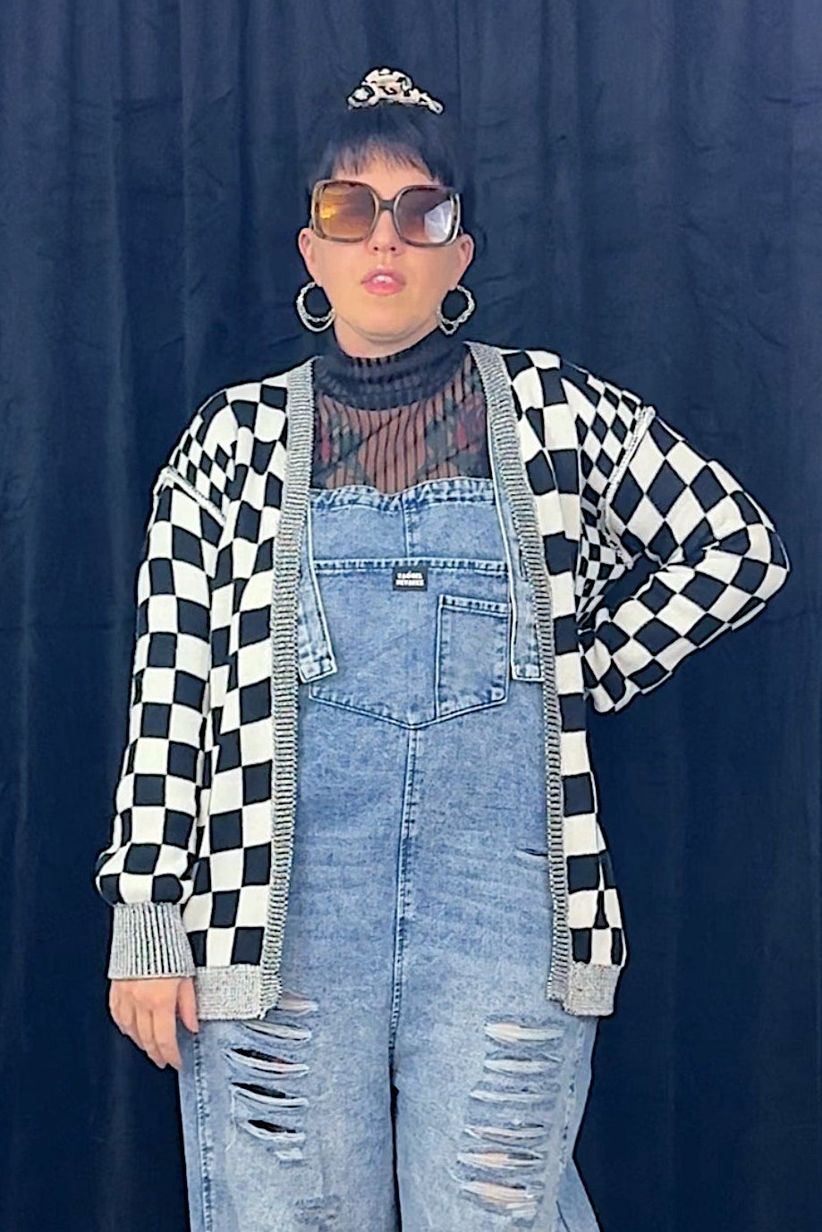 woman in sunglasses wearing overalls and black and white checkered cardigan