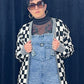 woman in sunglasses wearing overalls and black and white checkered cardigan