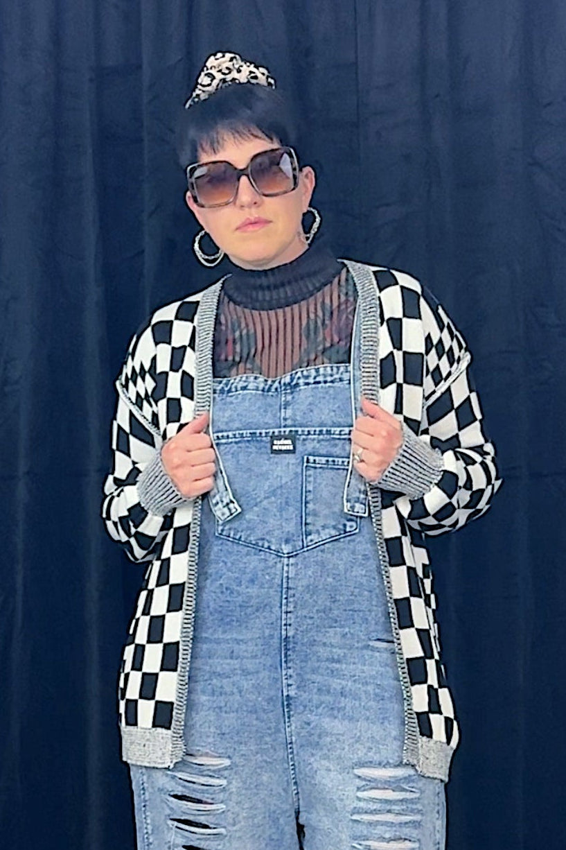 woman in sunglasses wearing overalls and black and white checkered cardigan