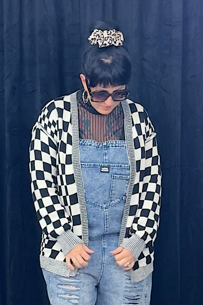 woman in sunglasses wearing overalls and black and white checkered cardigan