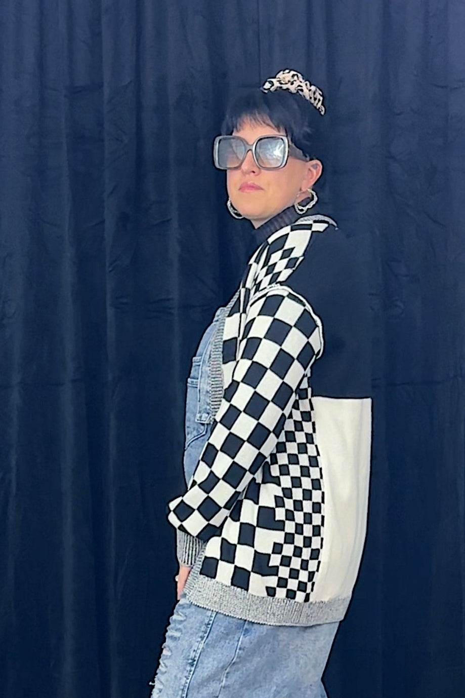woman in sunglasses wearing overalls and black and white checkered cardigan
