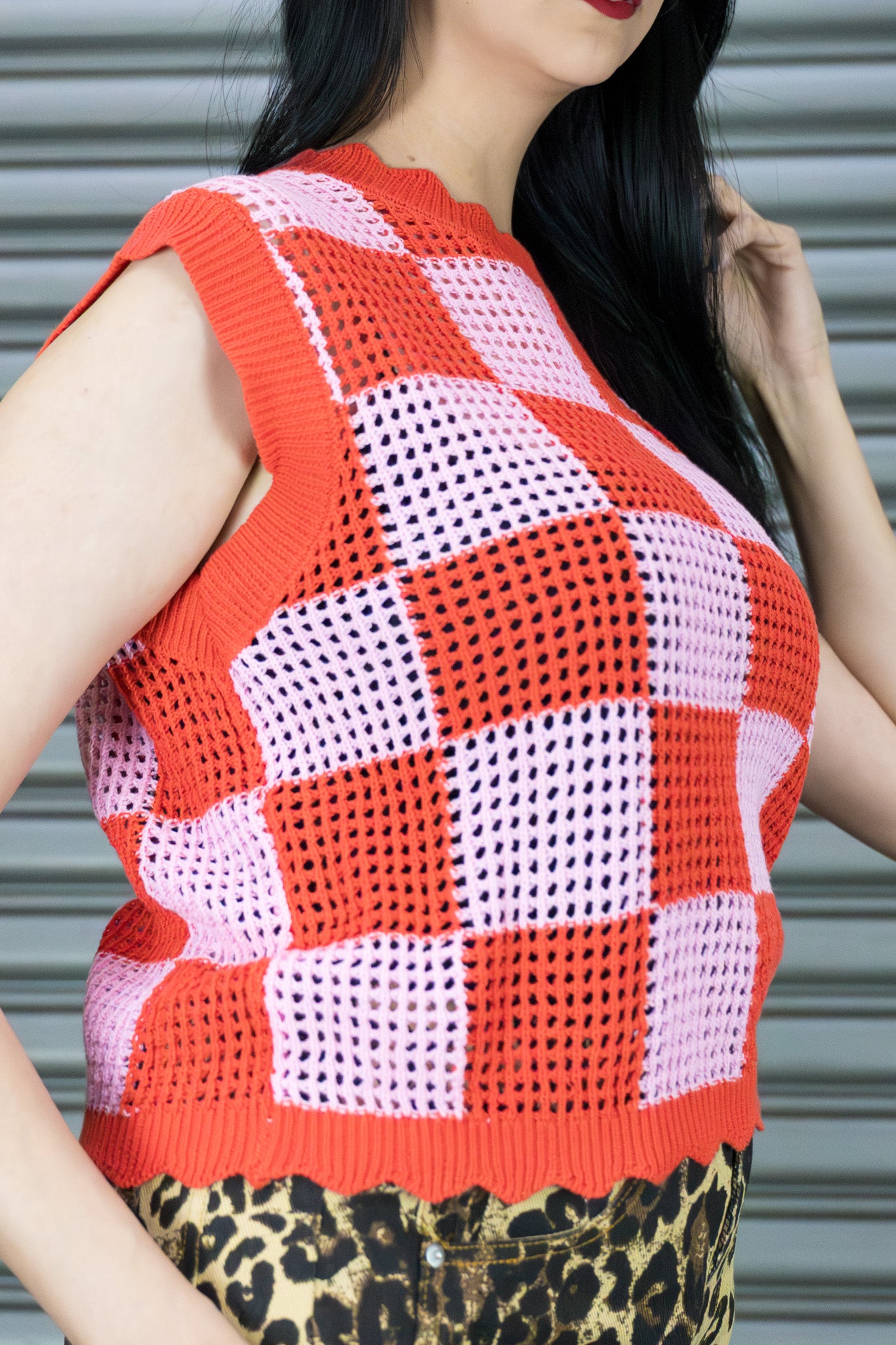 Person wearing a red and pink checkered sleeveless top with a leopard print skirt.