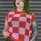 Person wearing a red and pink checkered sleeveless top with a leopard print skirt against a metallic shutter background.