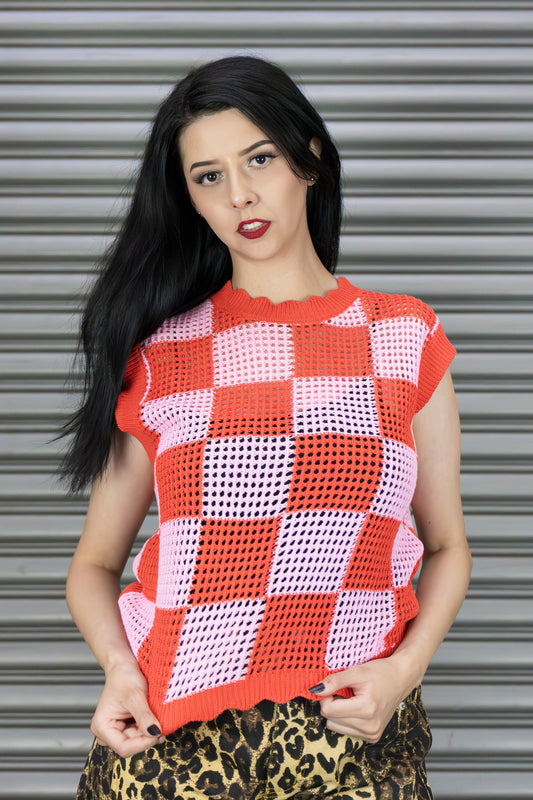 Woman wearing a red and pink checkered sleeveless top against a metallic shutter background