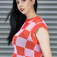 Woman wearing a red and pink patterned sleeveless top against a gray background