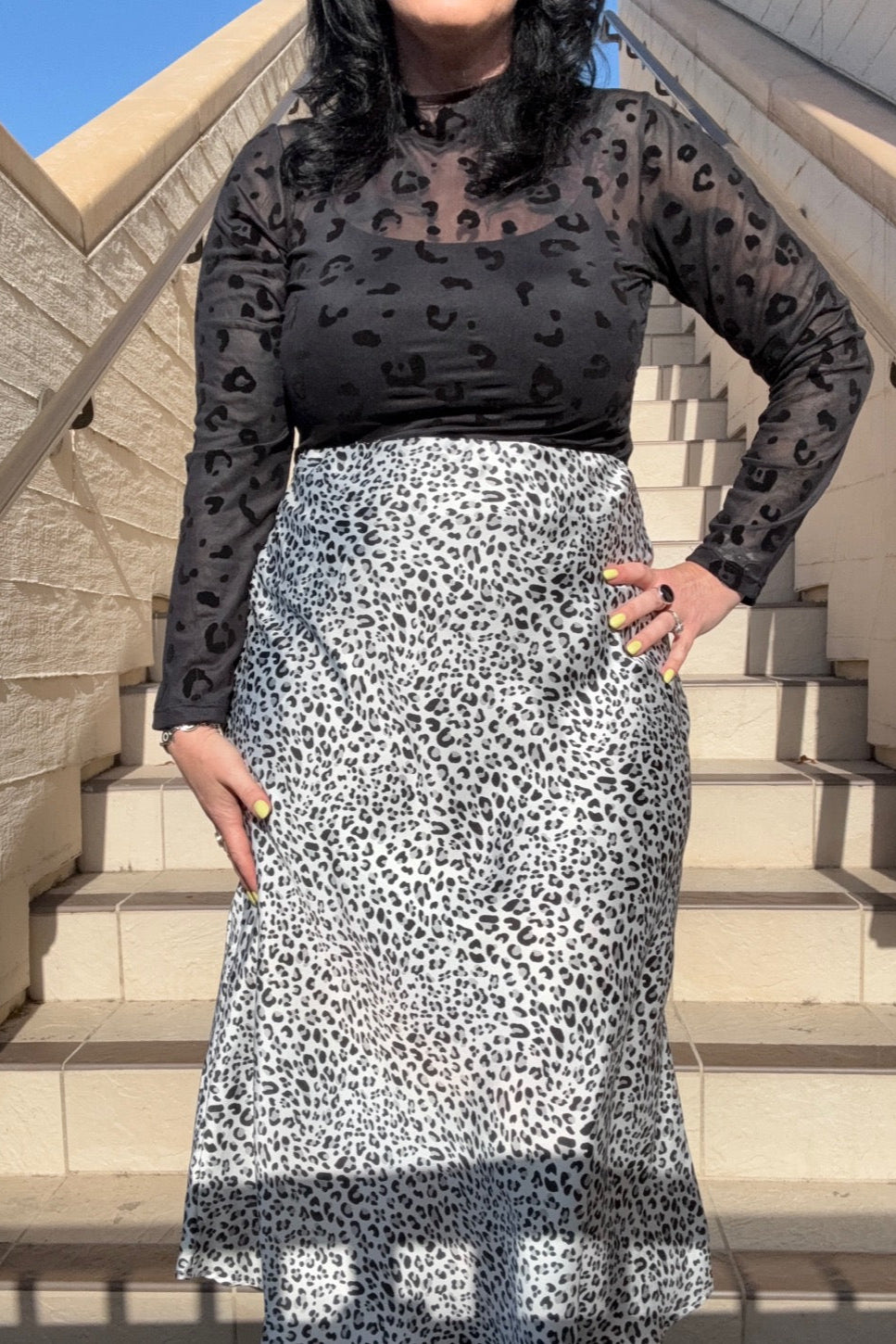 Person wearing a black and white leopard print outfit on stone steps.