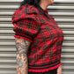 Person wearing a red plaid shirt with black trim against a metallic background