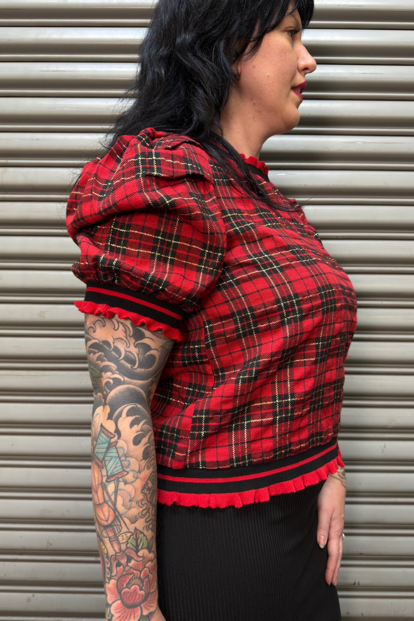 Person wearing a red plaid shirt with black trim against a metallic background