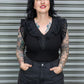 Woman wearing a black top with lace details and dark pants against a metal shutter background