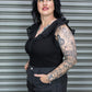 Woman wearing a black outfit with lace details against a metal shutter background