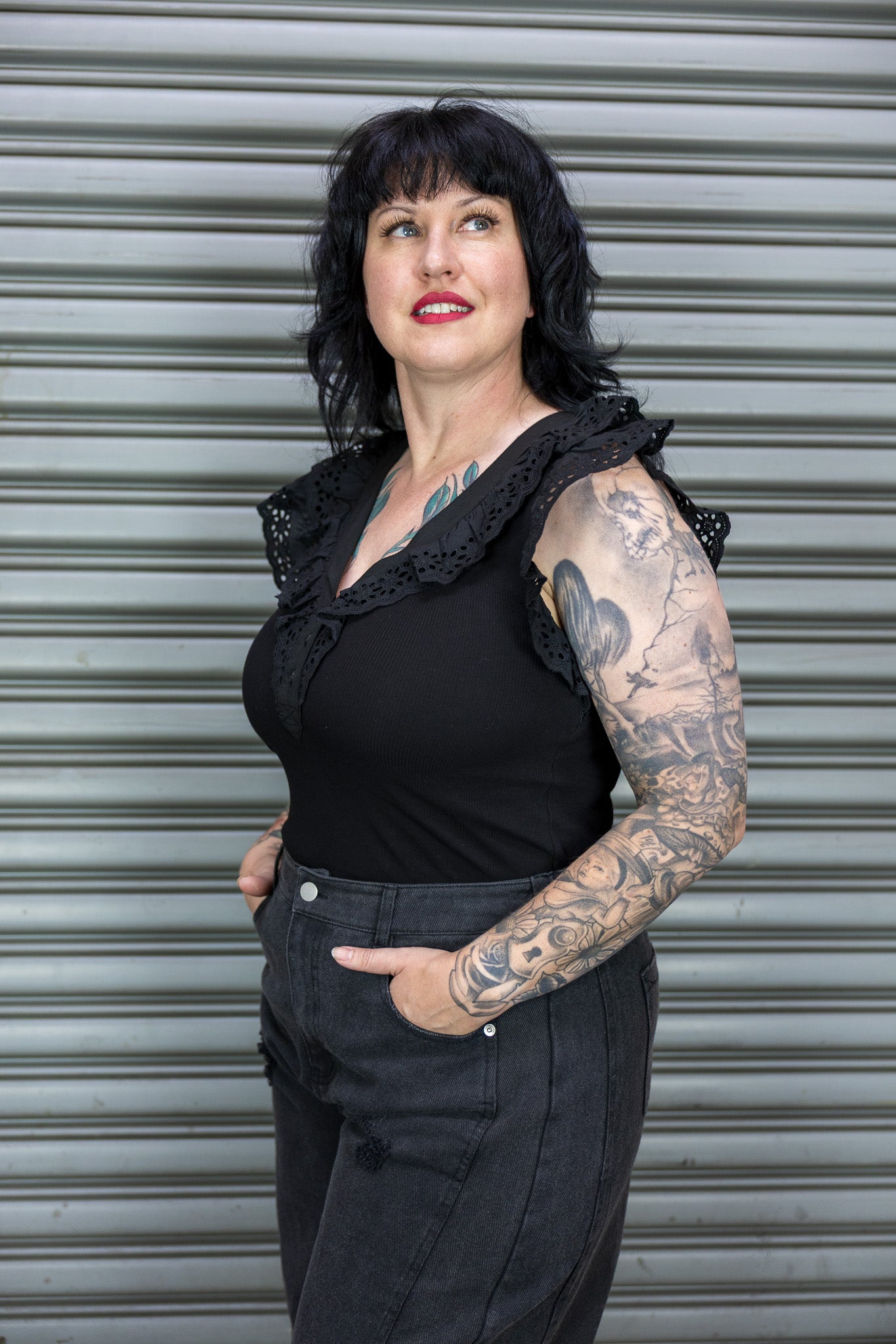 Woman wearing a black outfit with lace details against a metal shutter background