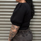 Person wearing a black top and gray pants against a metallic shutter background