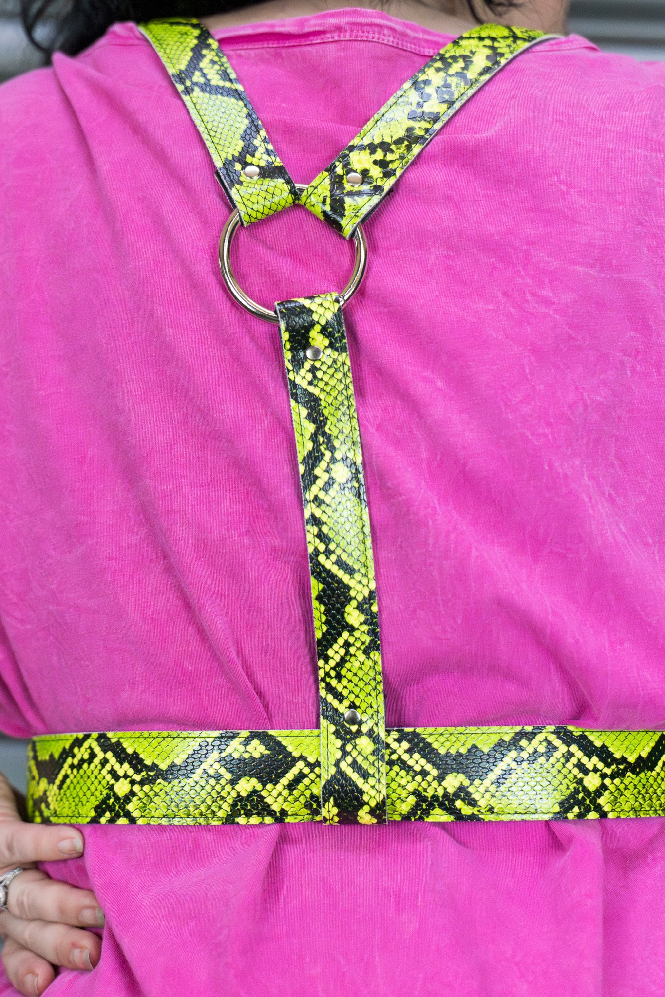 Person wearing a pink shirt with a yellow and black snake pattern harness.