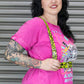 Woman wearing a bright pink t-shirt with a graphic design, standing in front of a metallic shutter.