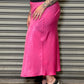 Person wearing a bright pink skirt standing against a metallic shutter.