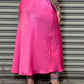 Person wearing a bright pink skirt standing in front of a closed metal shutter.