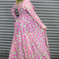 Person wearing a pink and green patterned dress standing in front of a metallic shutter.