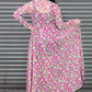 Person wearing a pink and green patterned dress against a metallic shutter background