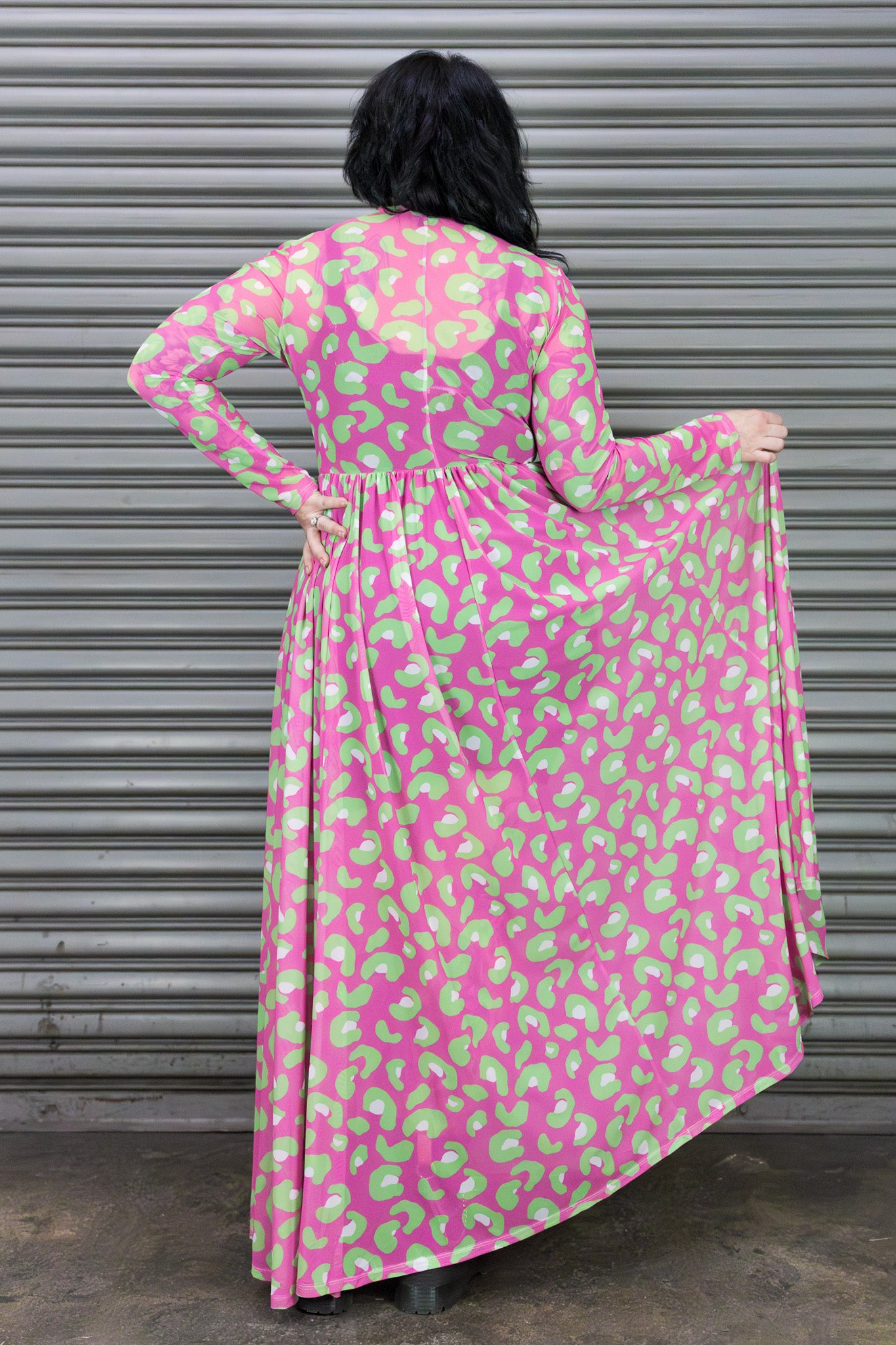 Person wearing a pink and green patterned dress against a metallic shutter background