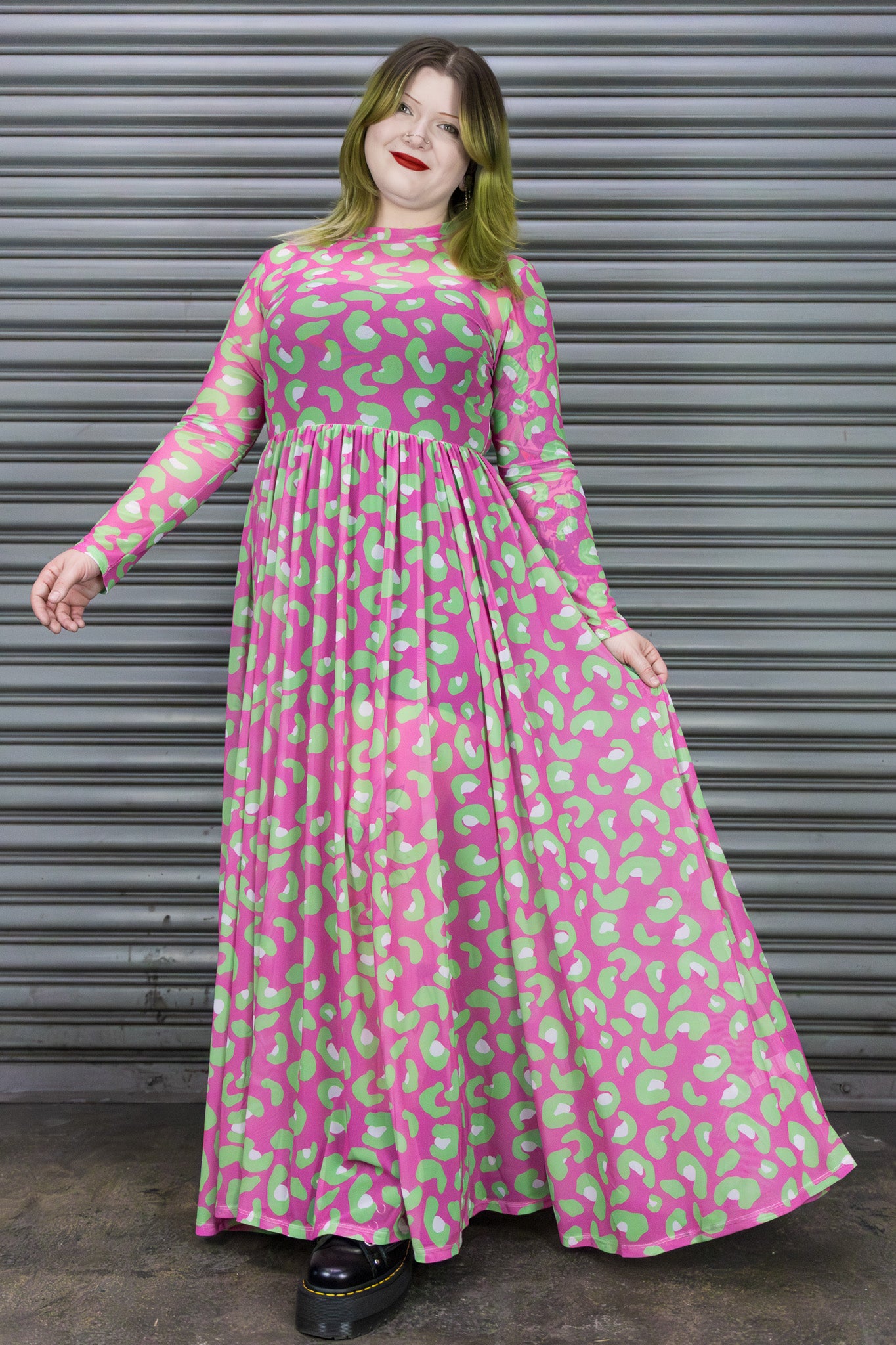 Person wearing a pink dress with green and pink leopard print against a metallic shutter background