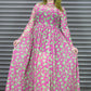 Woman wearing a pink dress with green pattern standing in front of a metallic shutter.
