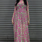 Woman wearing a pink and green patterned dress standing in front of a metallic shutter.