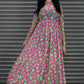 Woman wearing a pink and green patterned dress standing in front of a metallic shutter.