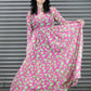 Woman wearing a pink and green patterned dress against a metal shutter background