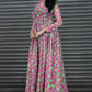 Woman wearing a pink and green patterned dress against a metallic shutter background