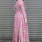 Woman wearing a pink and green patterned dress standing in front of a metallic shutter.