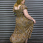 Woman in a patterned dress standing against a metal shutter.