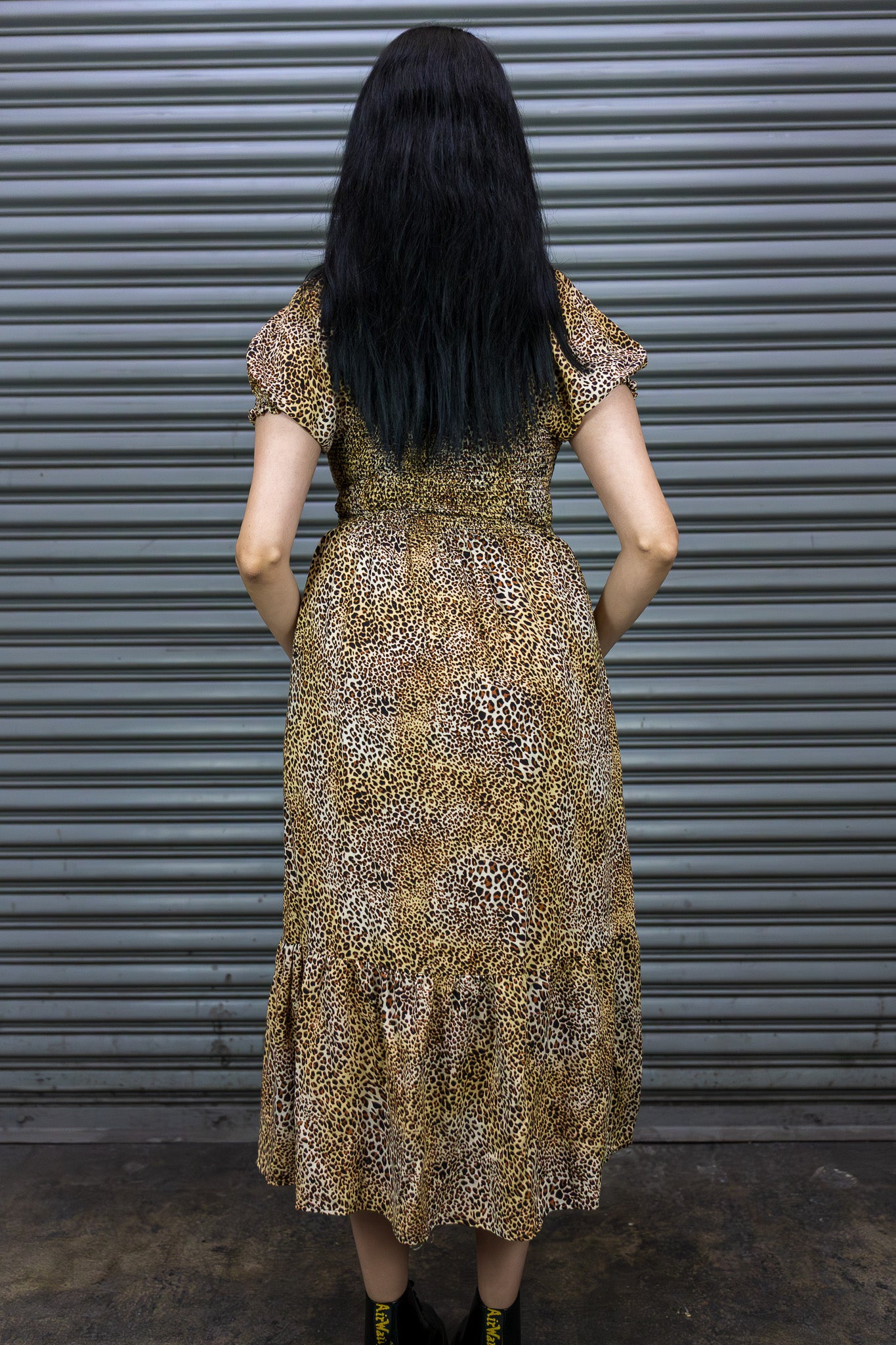 Woman wearing a patterned dress standing in front of a metallic shutter.