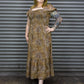 Woman wearing a patterned dress standing in front of a metallic shutter.