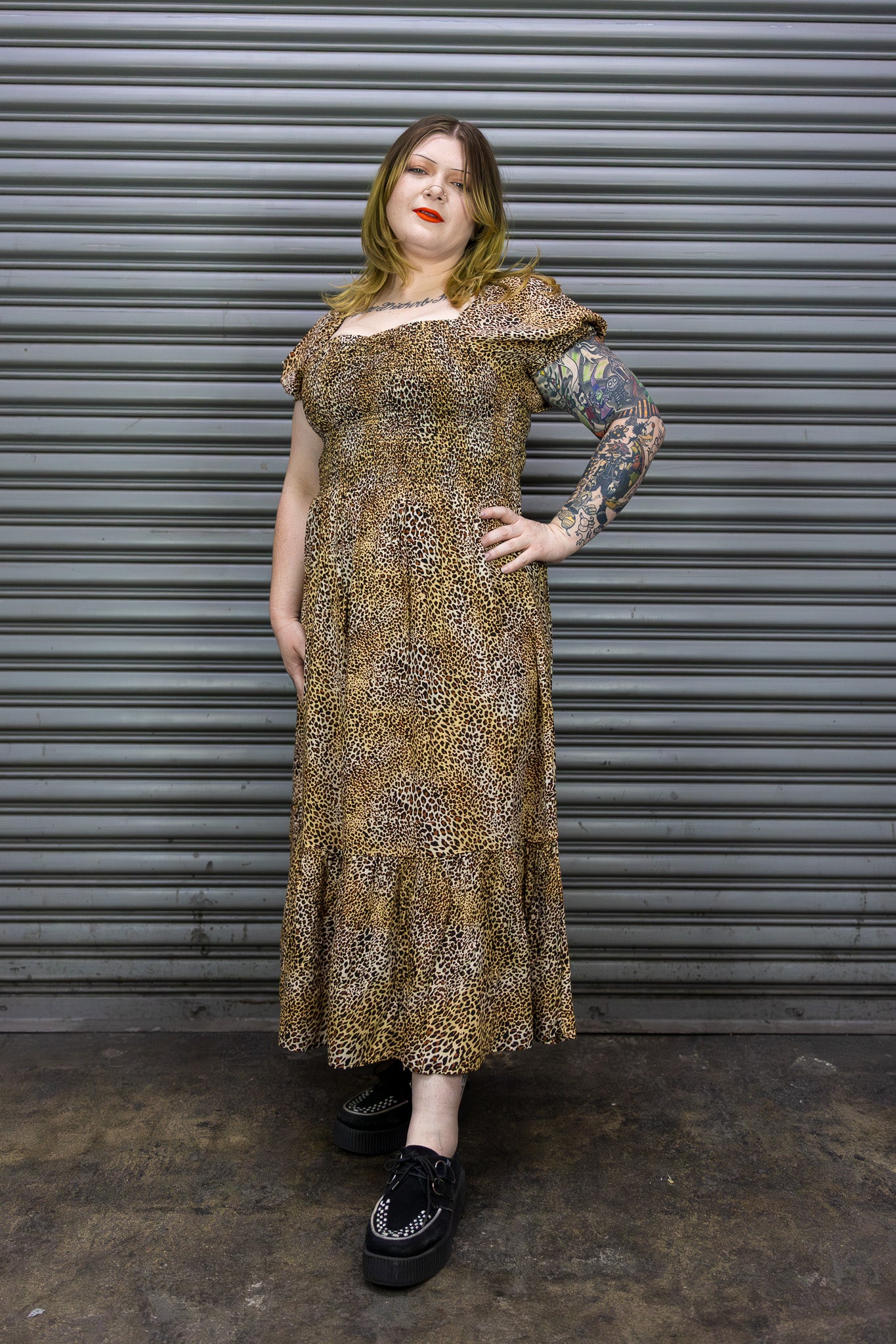 Woman wearing a patterned dress standing in front of a metallic shutter.