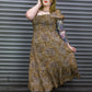Woman wearing a patterned dress standing against a metallic shutter.