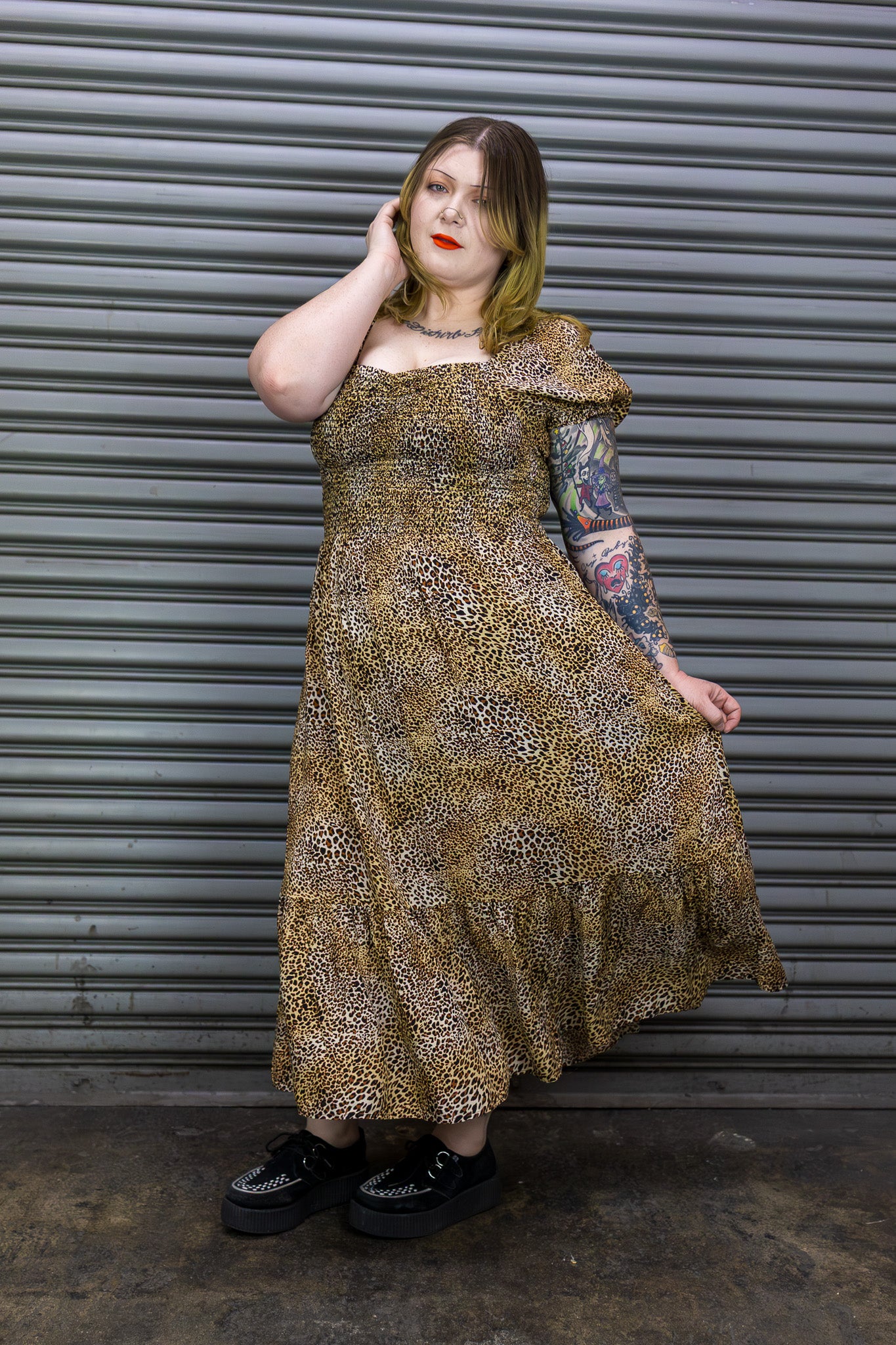 Woman wearing a patterned dress standing against a metallic shutter.