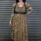 Woman wearing a patterned dress with tattoos standing in front of a metallic shutter.