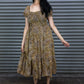 Woman wearing a patterned dress standing against a metallic shutter.