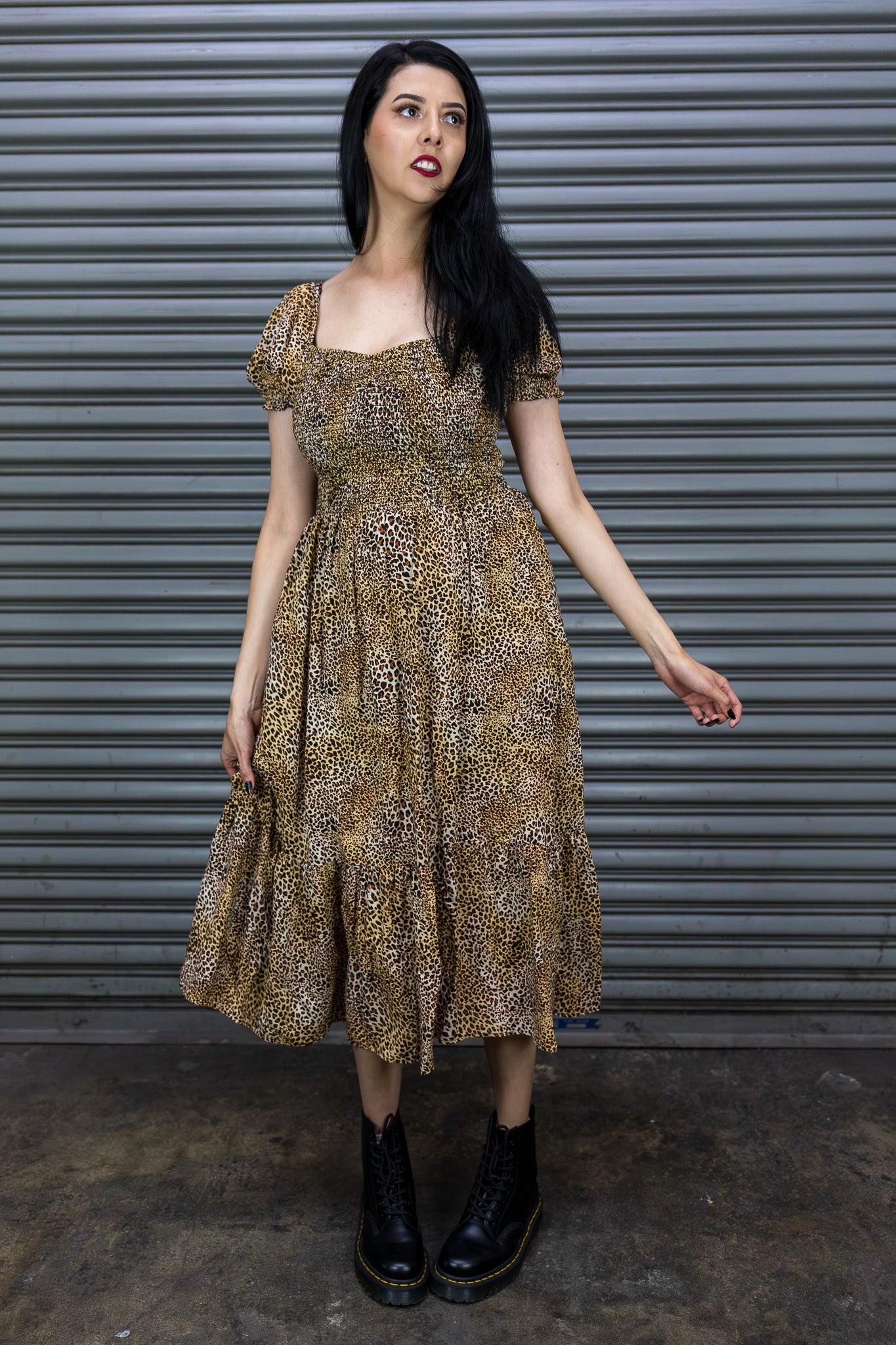 Woman wearing a patterned dress standing against a metallic shutter.