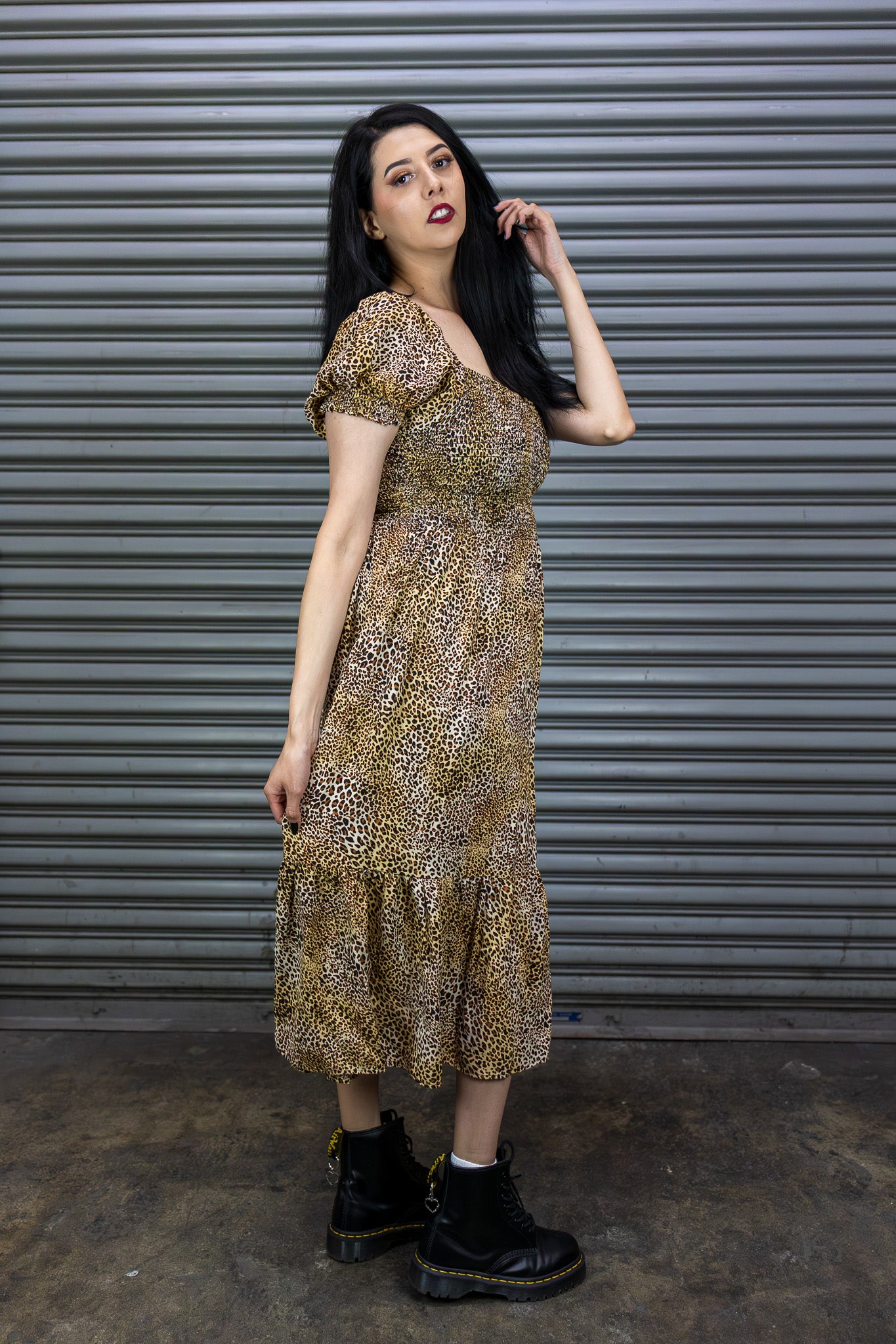 Woman wearing a patterned dress standing in front of a metallic shutter.