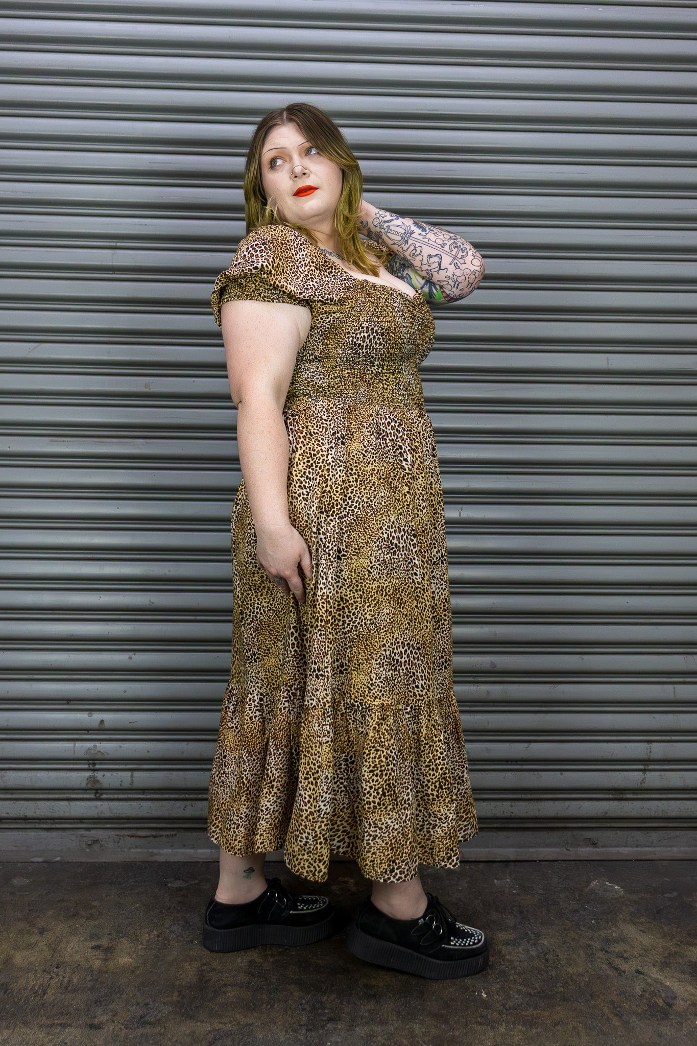 Woman wearing a patterned dress standing in front of a metal shutter.