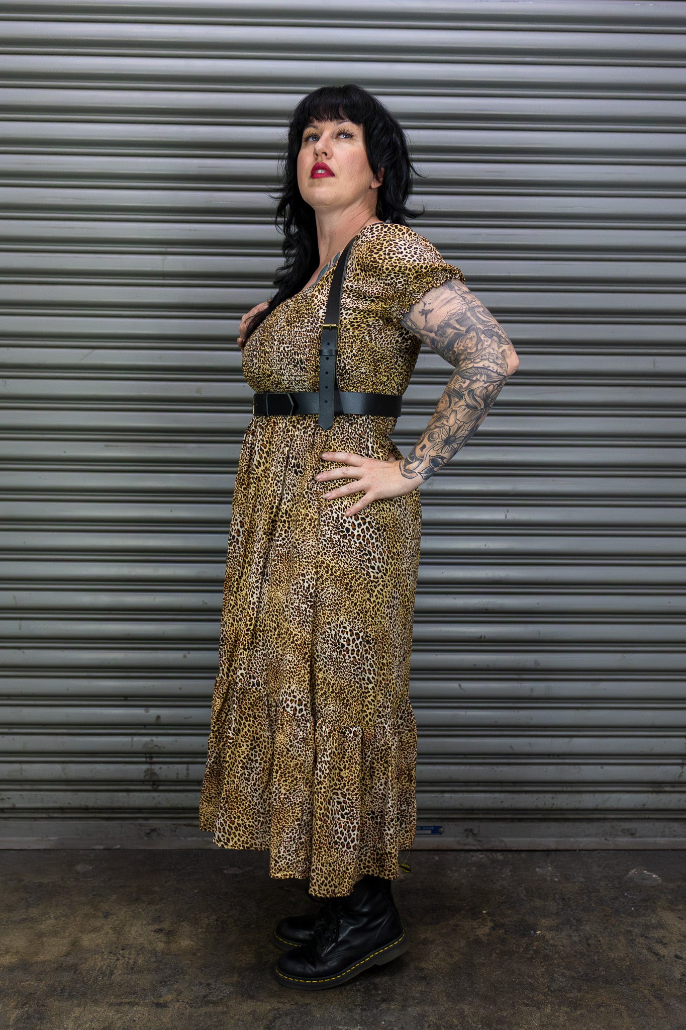 Woman in a patterned dress standing in front of a metal shutter.